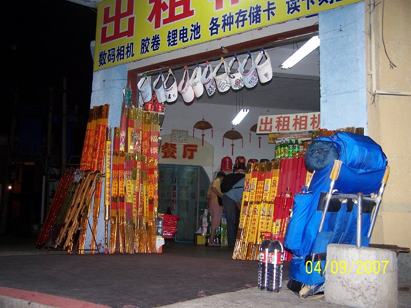 100_3431.JPG - Pred obchodom blzko vchodu na vstup na horu Tajan. Okrem nho batohu vidno zpaln palice pre nske svtyne. ***** In front of a shop near the entrance to the route to the mount Tai. Except our backpack, you can see inflammable sticks for Chinese temples.