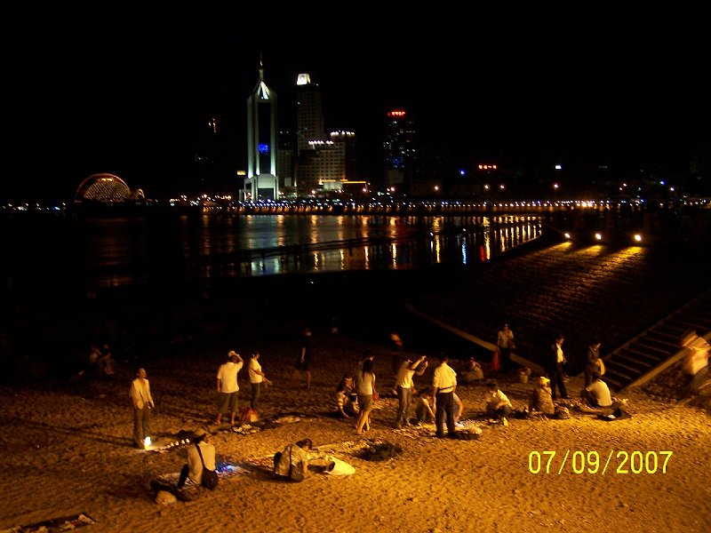 100_3688.JPG - Veern hra svetiel v chingtao. udia na pli zbieraj vyplaven poklady mora a predvaj ich. ***** Evening play of lights in Qingdao. People on the beach collect sea fruits washed up and sell them.